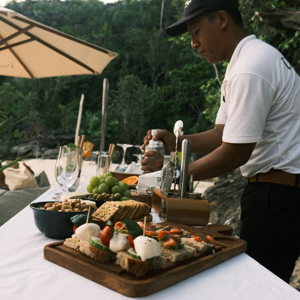 Bartender preparing signature cocktails on the beach for guests of Pacific High’s luxury yacht charter in Raja Ampat, Indonesia.
